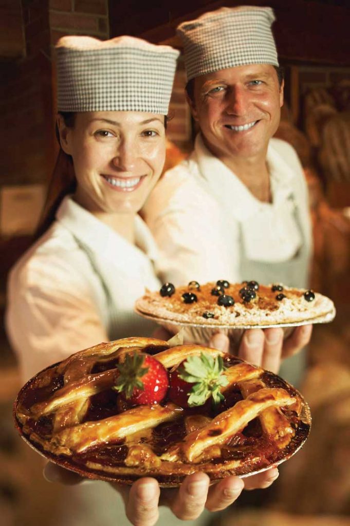 Two bakers showing off their pies