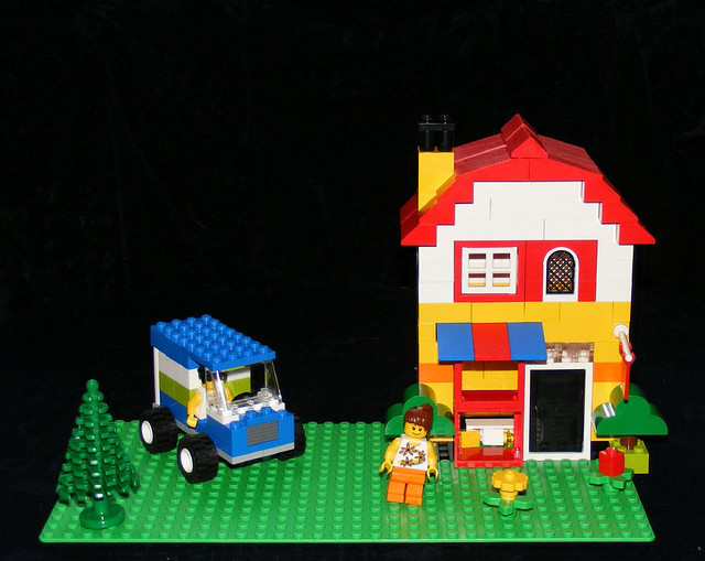 A Lego House with a car and two happy people.