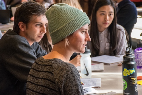 Three individuals actively listening to a speaker