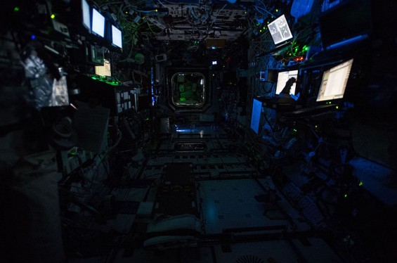 Picture of the interior of the International Space Station with its lights off to mimic nigh-time