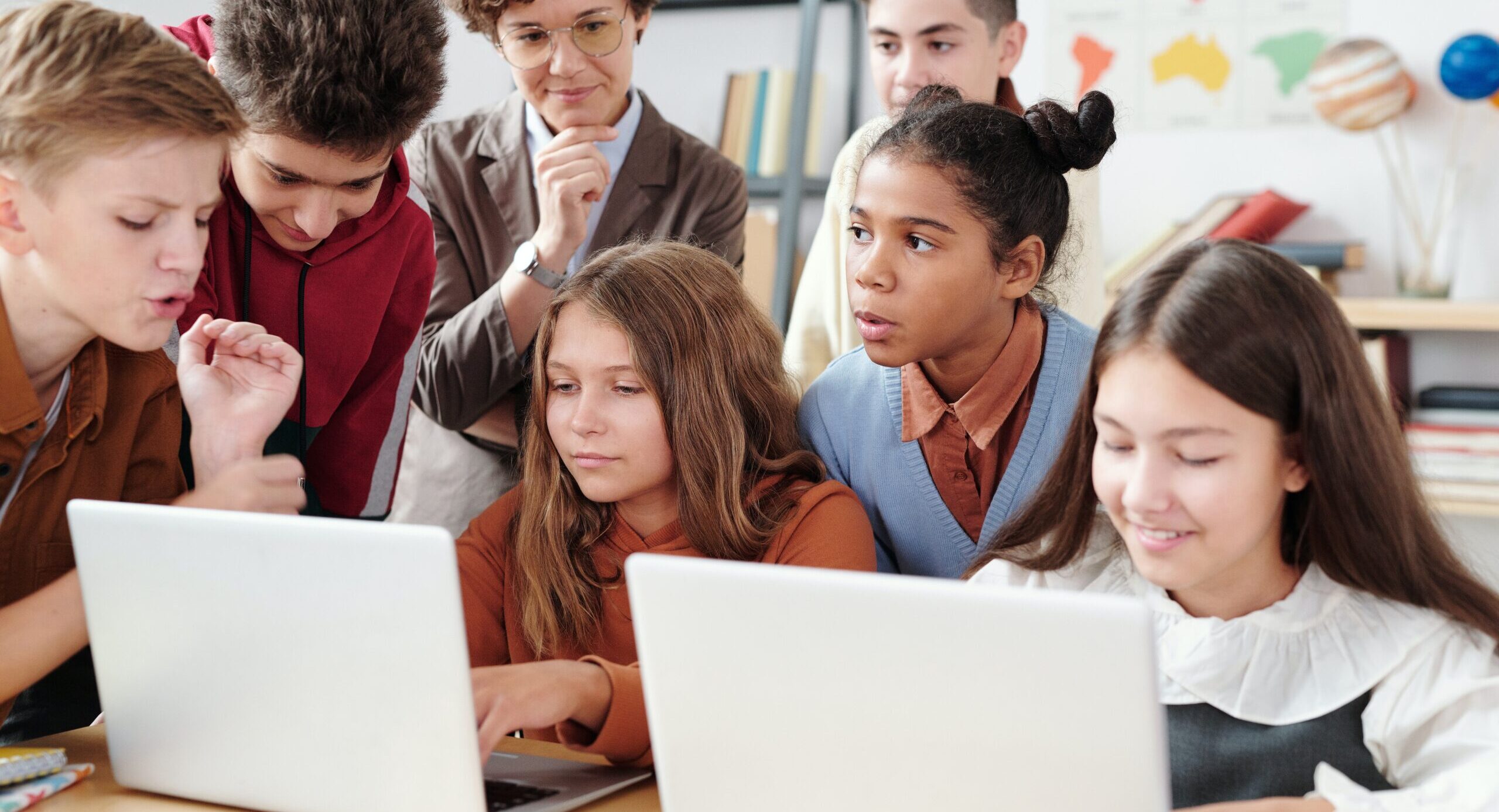 Children huddled around laptops in class