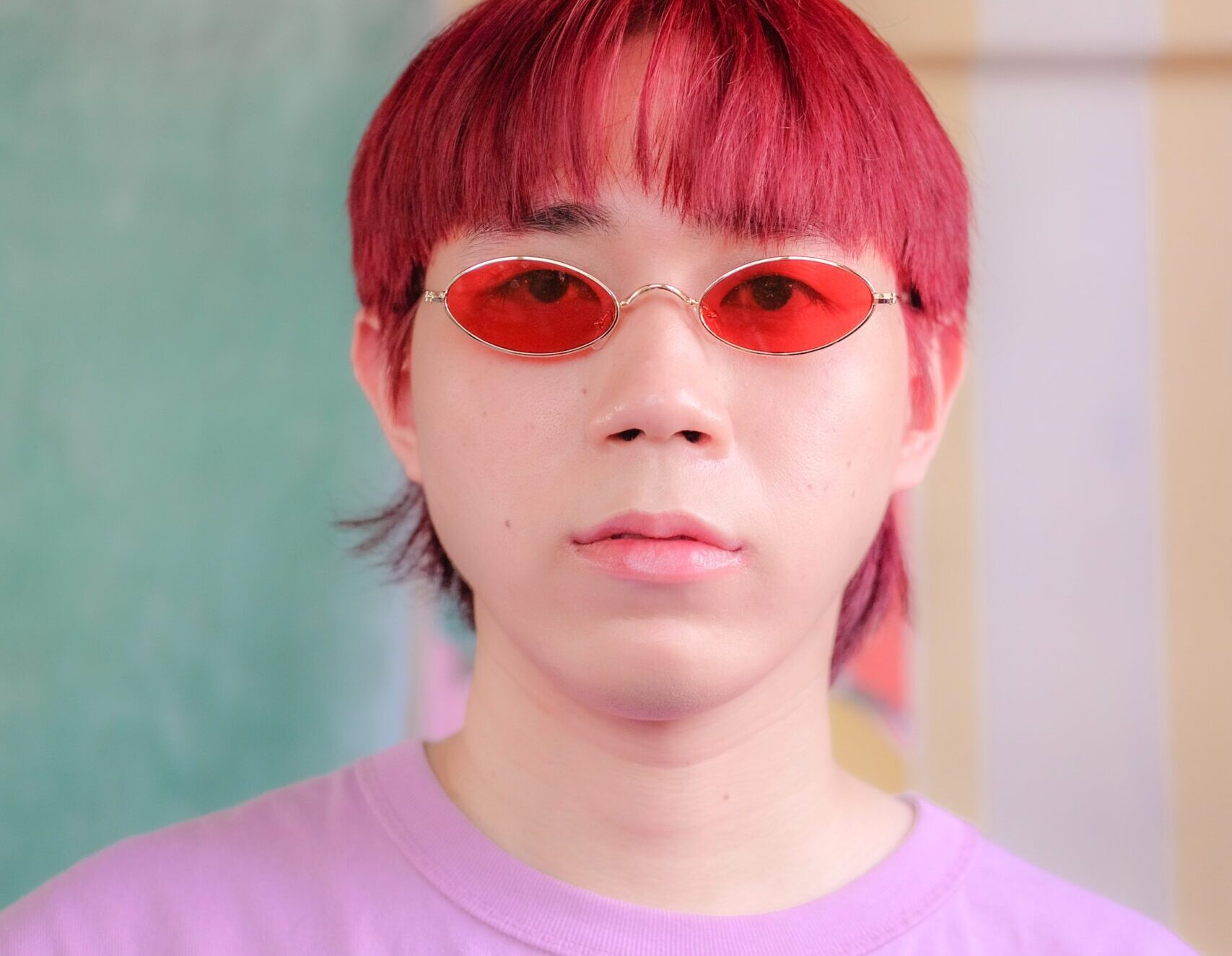 Man wearing red-tinted glasses and a pink shirt